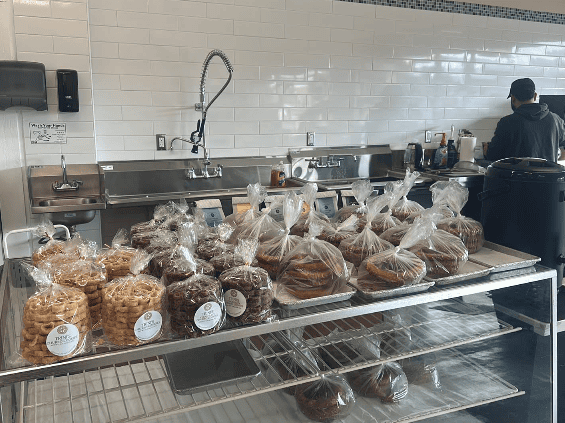 Café back counter with a metal rack of packaged baked goods and cookies